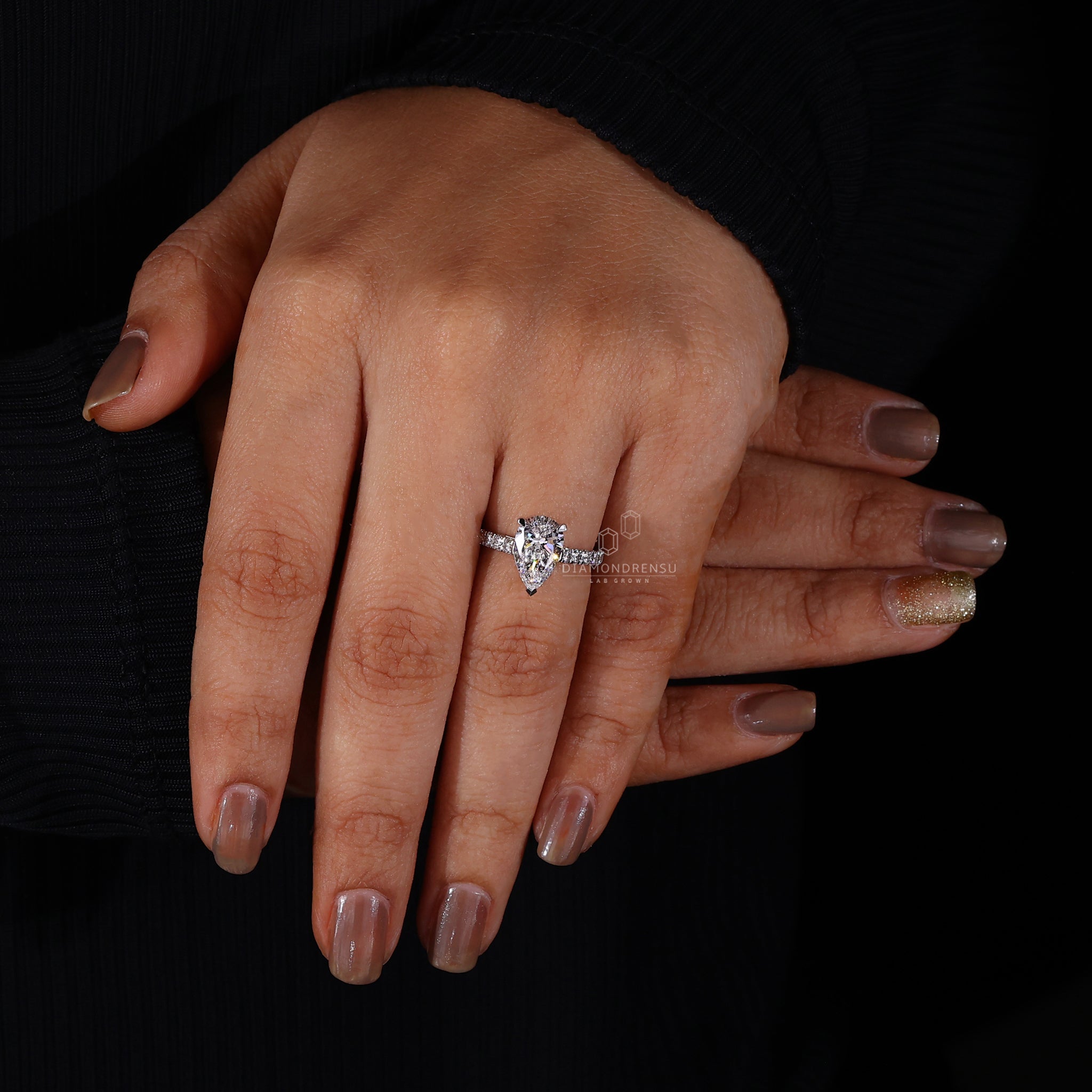 Pear shaped diamond ring with pave diamond accents on a model