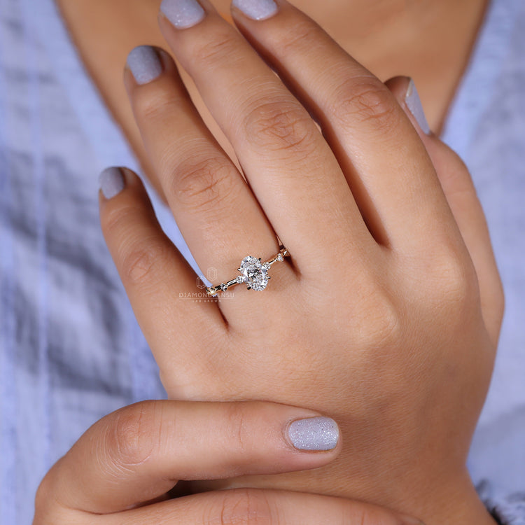 Hand showing a hidden halo engagement ring with a stunning oval cut diamond and yellow gold band.