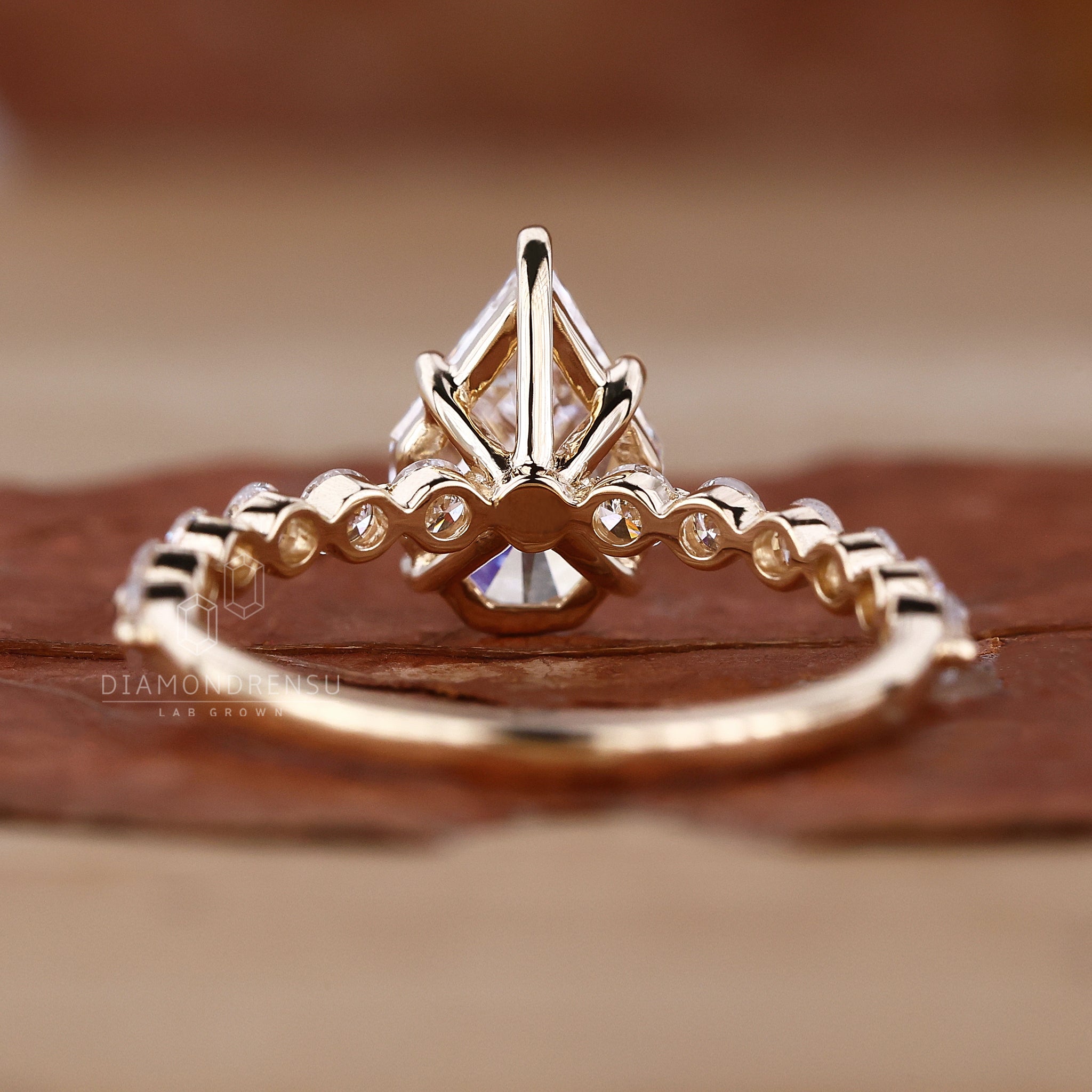 Detailed view of a yellow gold engagement ring with a spear cut diamond and pave diamonds.