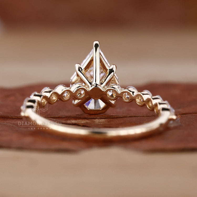 Detailed view of a yellow gold engagement ring with a spear cut diamond and pave diamonds.