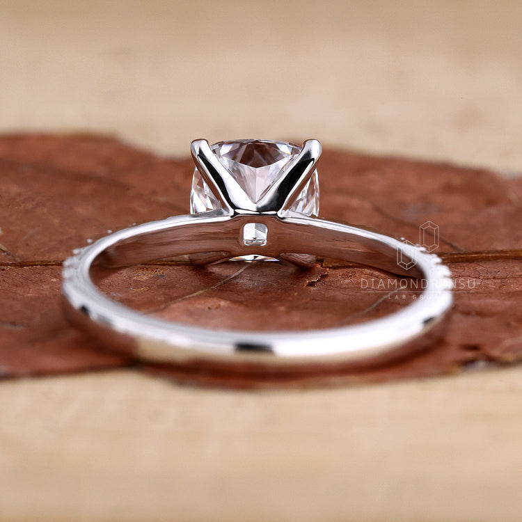 Cushion cut ring with a pave diamond band displayed on a velvet cushion.