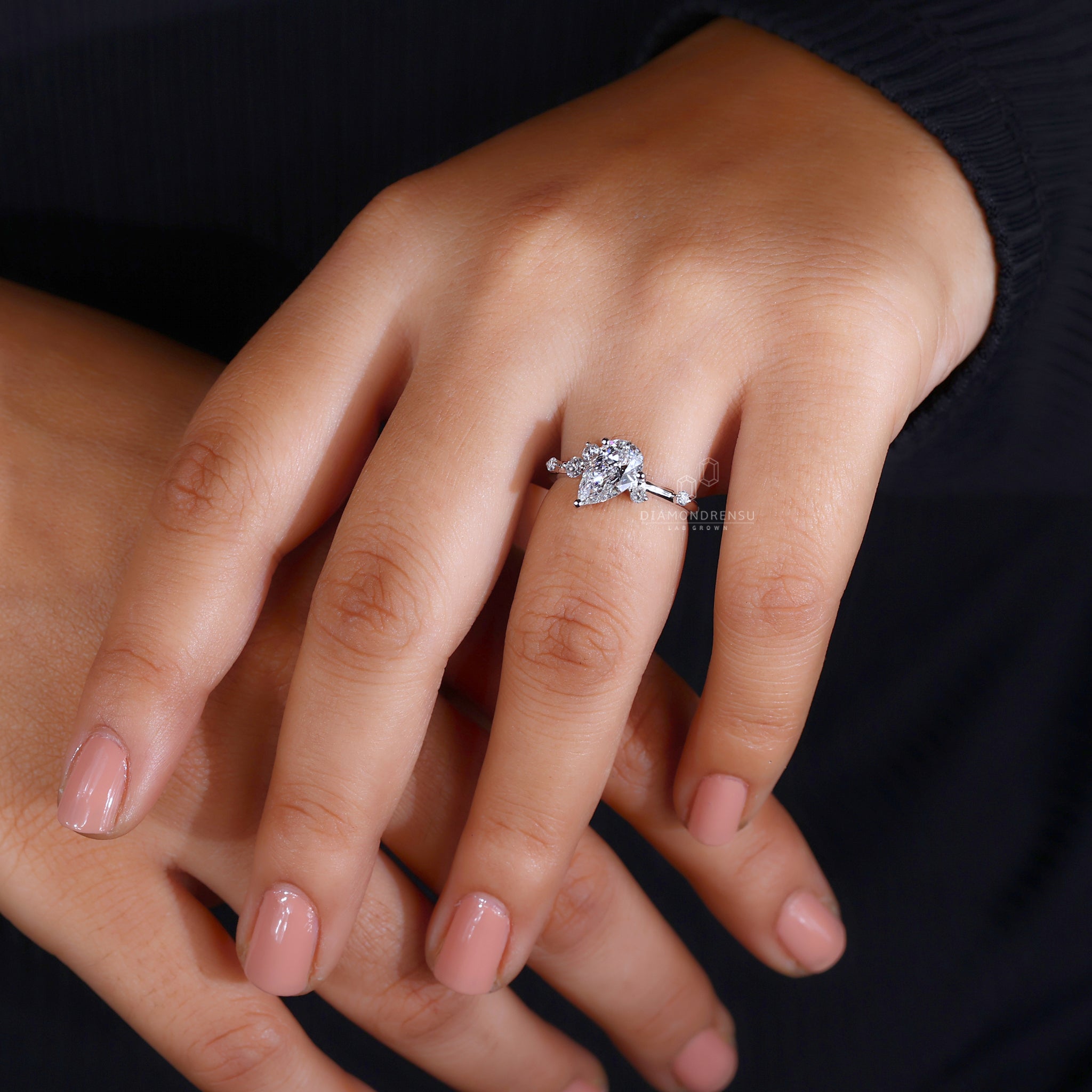 Model showcasing a pear cut diamond ring with a basket setting and round prongs