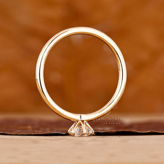Solitaire setting round brilliant cut diamond ring in yellow gold design.
