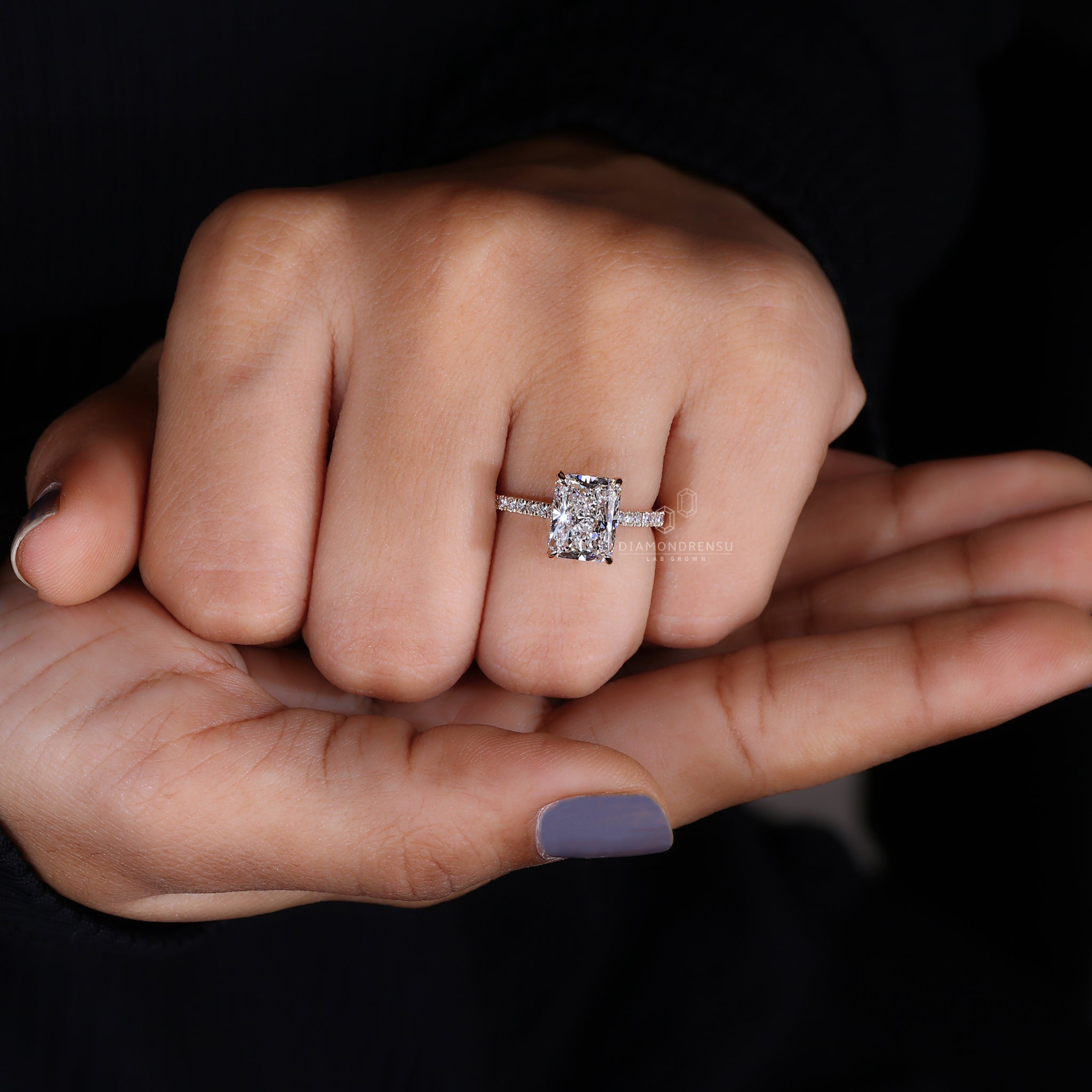 Radiant cut diamond ring on model's hand showcasing the brilliance of the pave diamond band and yellow gold setting