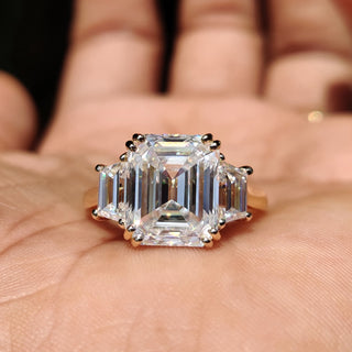 Three stone engagement ring with a stunning emerald cut moissanite center.
