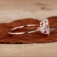 Oval engagement ring with pear side stones on a display stand