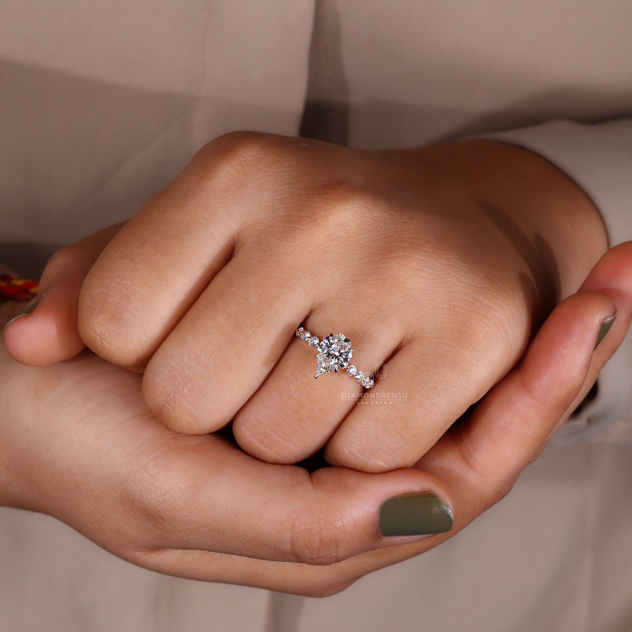 Model wearing a spear cut diamond ring with yellow gold and claw prongs.