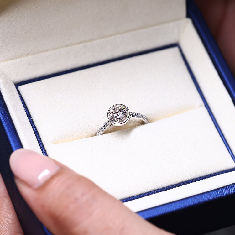 Bezel setting ring featuring round cut diamond and two row pave band.
