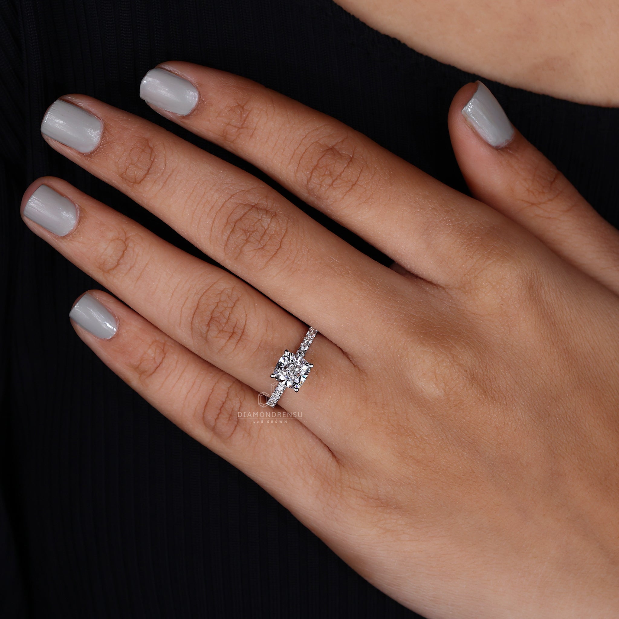 Lab-grown cushion cut diamond ring worn by a smiling woman.