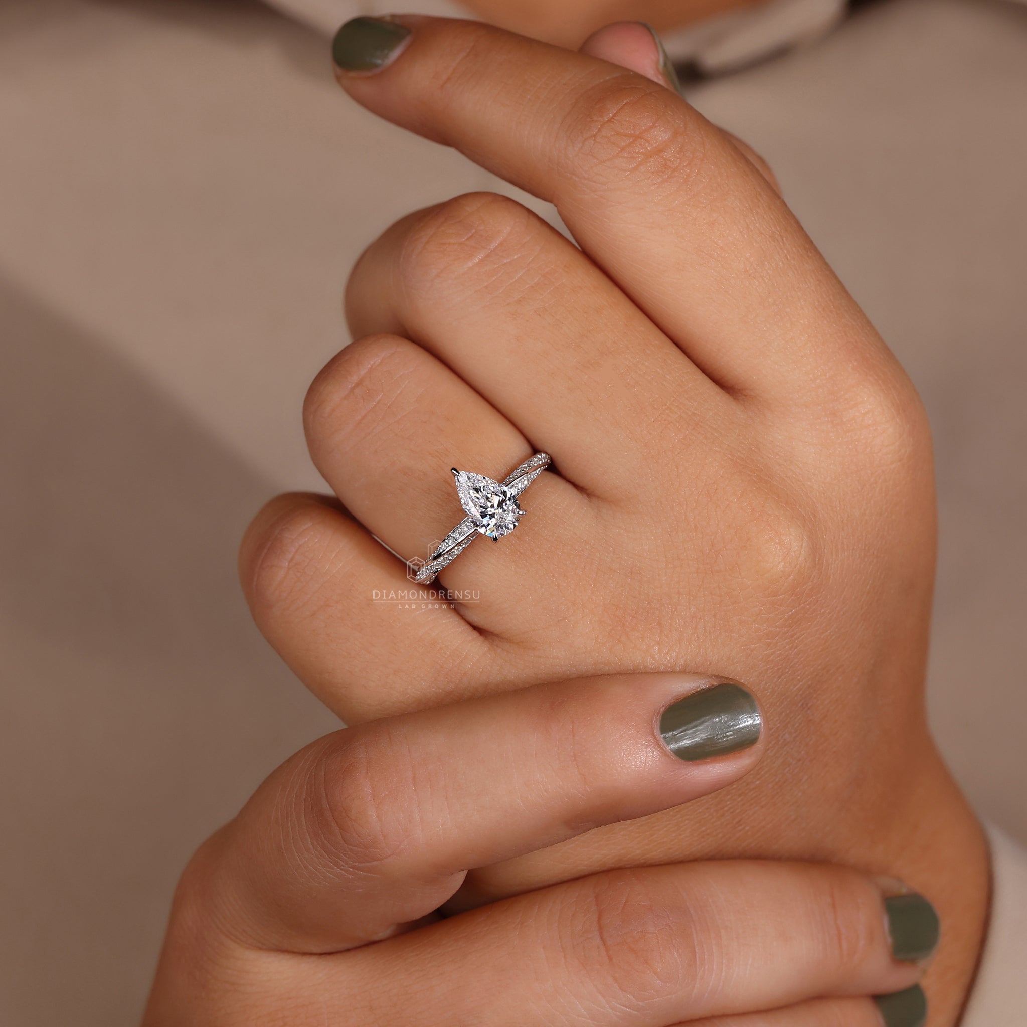 Pear shaped diamond ring with claw prongs showcased on a model's hand.