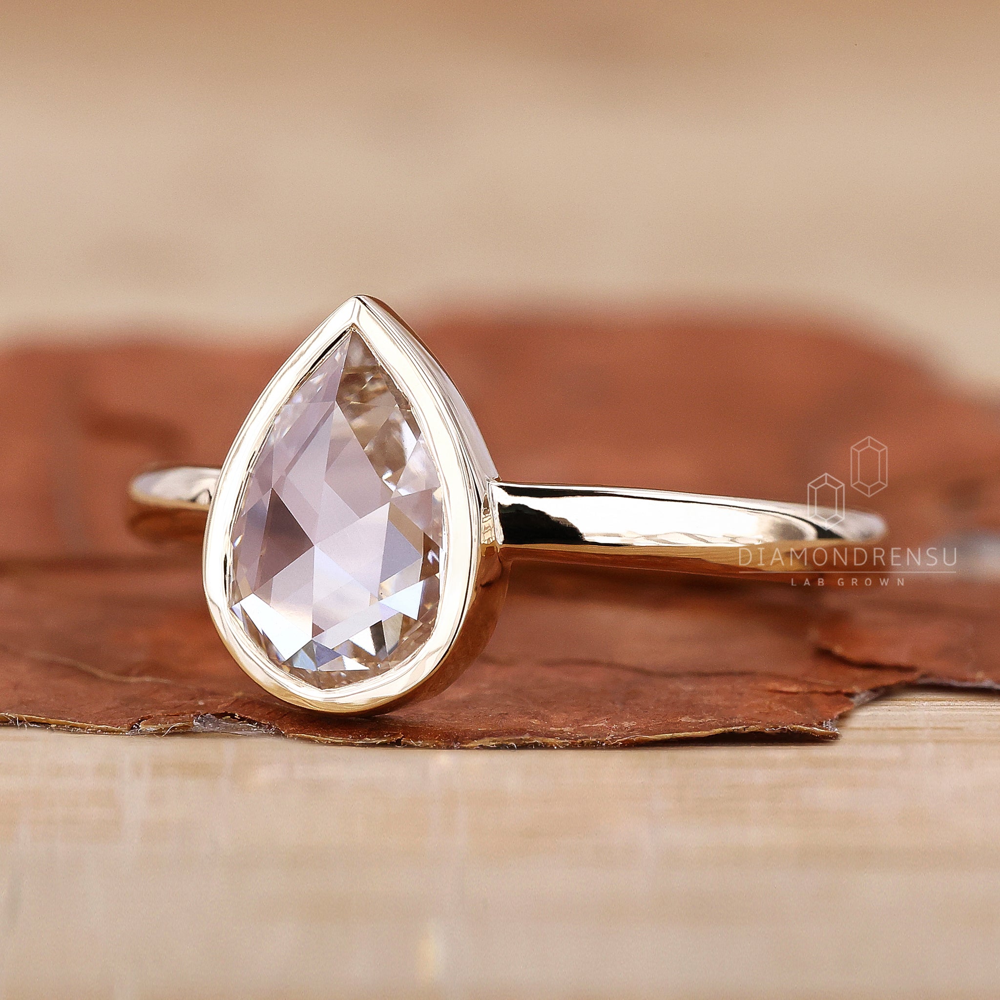 Stunning bezel pear engagement ring with sleek design.
