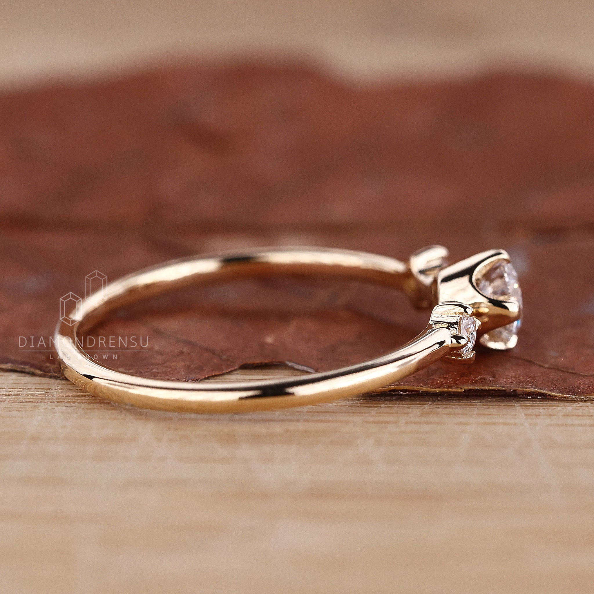 Round engagement ring with side stones, set in yellow gold with compass prongs for added brilliance.