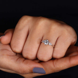 Hand wearing a round diamond ring with pear side stones, emphasizing its unique charm and brilliance.
