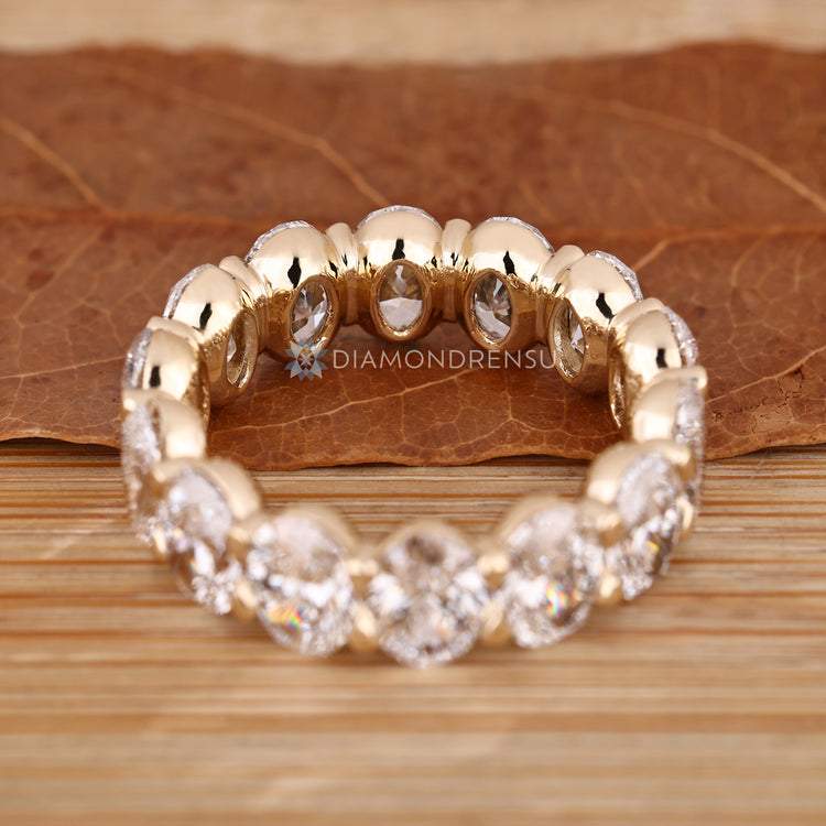 Oval diamond wedding band with handcrafted bezel basket design.