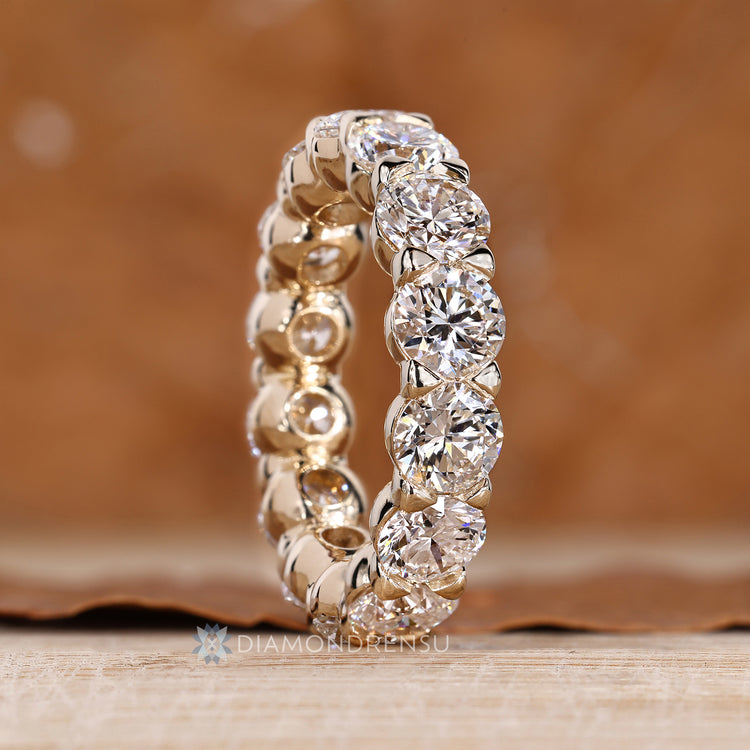 Round diamond wedding band with bezel basket and shared prong details.