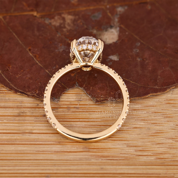 Custom engagement ring in yellow gold with oval center and round side stones.
