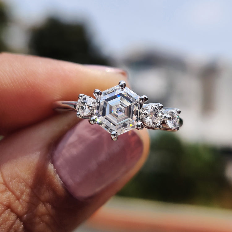 Hexagon step cut engagement ring with prong setting and round cut side stones