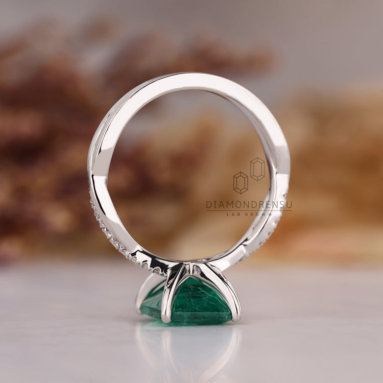 Custom diamond ring with emerald birthstone and twisted shank style.
