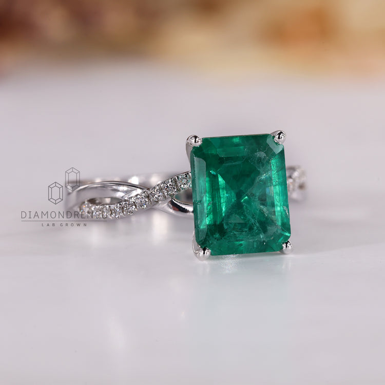 White gold ring featuring emerald birthstone with four prong setting.
