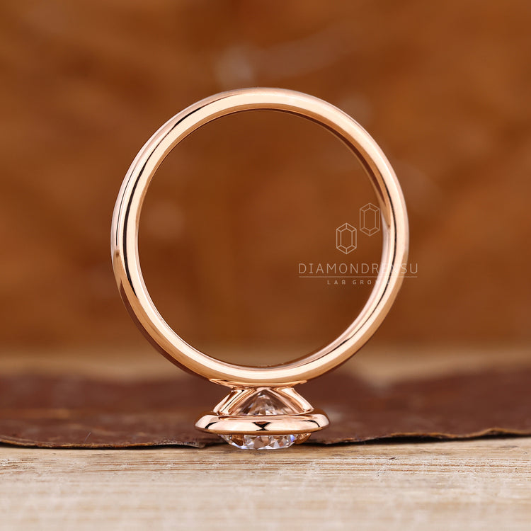 Custom engagement ring in rose gold with bezel set and halo diamonds.
