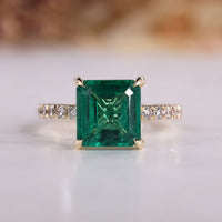 Asscher cut engagement ring with emerald gemstone.
