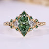 Green marquise engagement ring with trillion side stones and emerald gemstone.