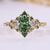 Green marquise engagement ring with trillion side stones and emerald gemstone.