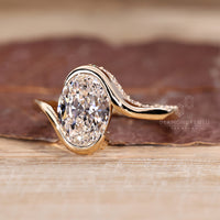 Oval cut diamond ring with round cut pavé and bypass design.
