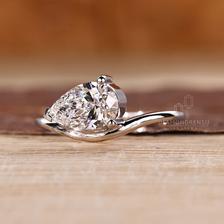 Custom pear diamond solitaire engagement ring set in elegant white gold.
