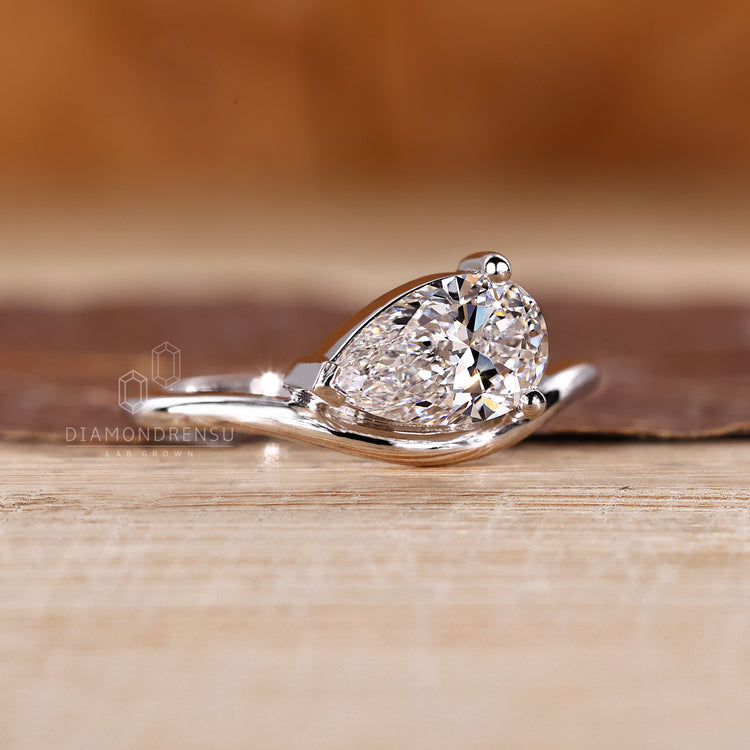 Diamondrensu engagement ring showcasing pear solitaire in east west style.
