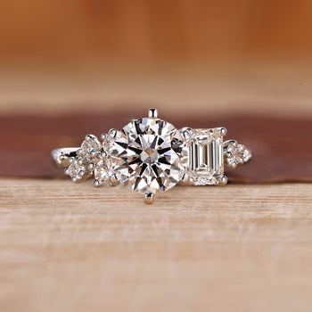Cluster diamond ring with emerald and round cut side stones
