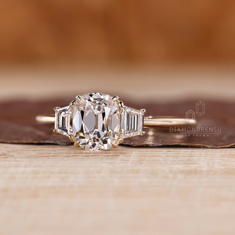 Cushion old mine diamond ring with trapezoid accents and prong setting.
