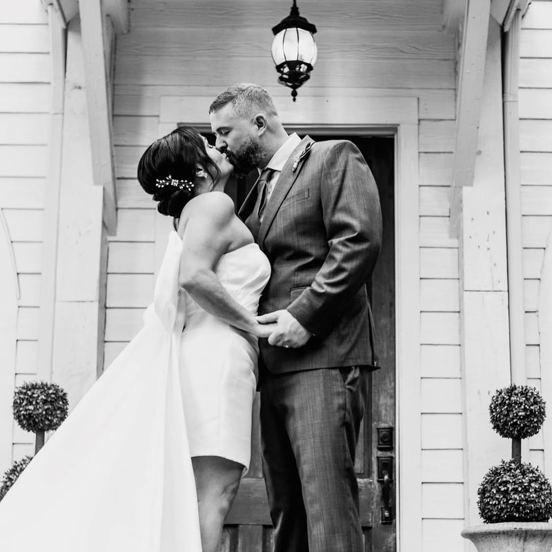 Bride in wedding gown and groom kissing in a doorway
