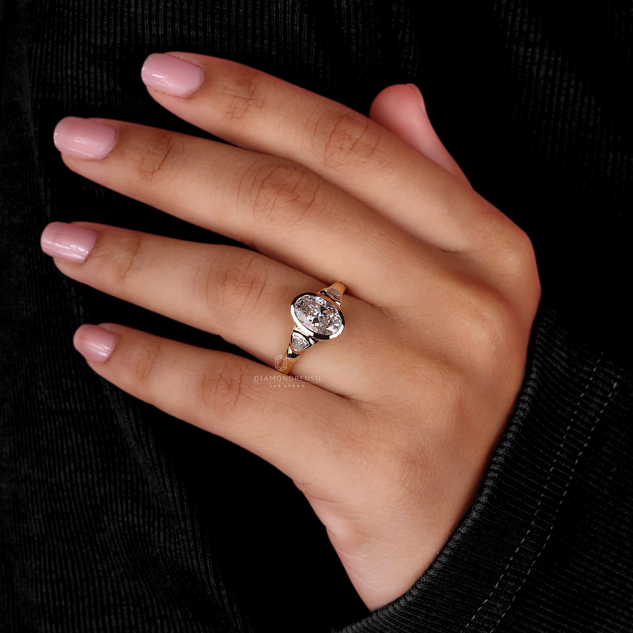 A hand adorned with a bezel set engagement ring, exuding modern elegance and understated charm.