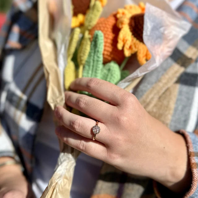 Close up of a hand holding a flower bouquet showing a gold wedding band
