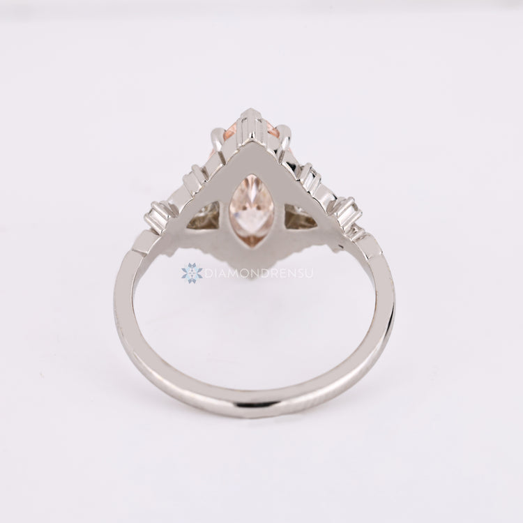 Pink marquise diamond ring featuring trillion and round side stones.