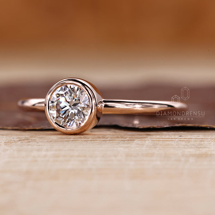Round cut diamond ring with secure bezel solitaire setting.