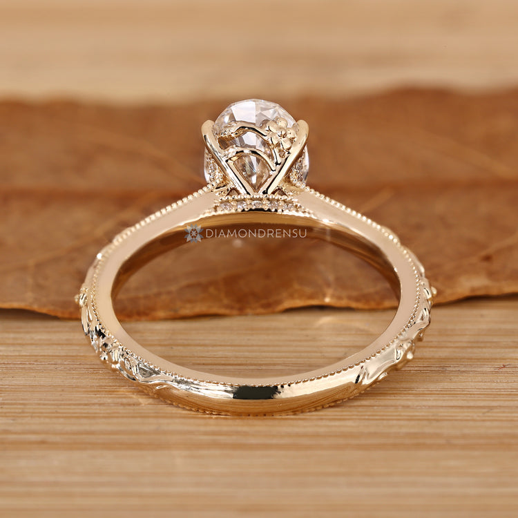 Oval ring with a botanical vine and leaf shank and milgrain details.