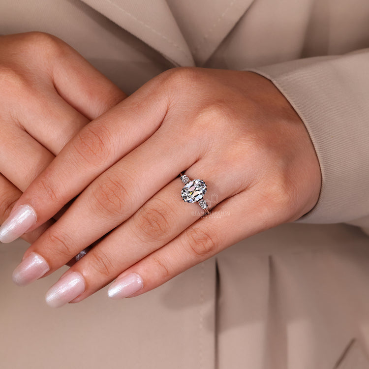Lab grown cushion old mine diamond ring with round side stones.
