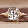 Solitaire engagement ring with cushion rose cut diamond and bezel setting.