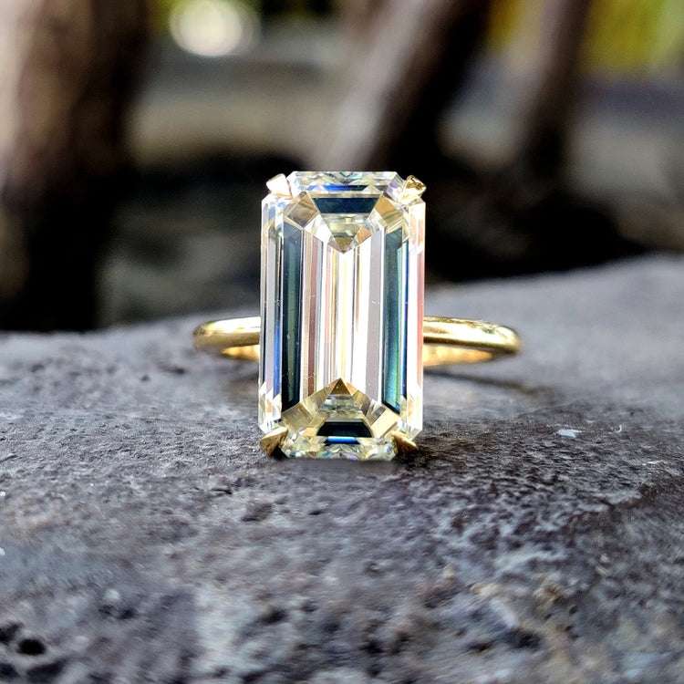 Emerald solitaire engagement ring placed in a sleek solitaire setting.
