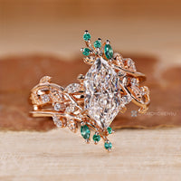 Six leaf style prong setting with round and marquise cut emerald gemstone.