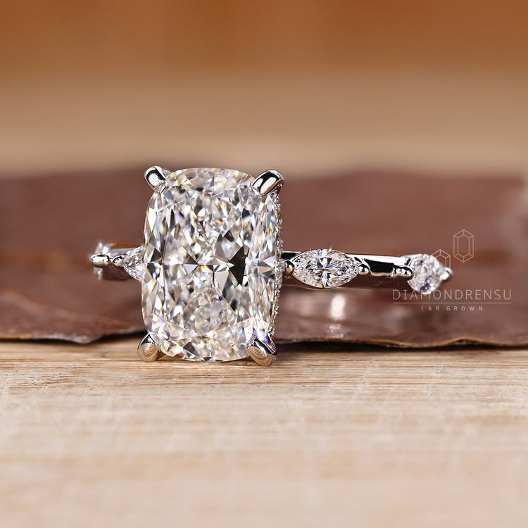 Elongated cushion cut engagement ring with four tab prong setting.