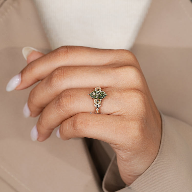 Marquise ring with a green center stone and six claw prong setting.