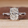 Elongated cushion cut diamond ring with distance pave setting and hidden halo.