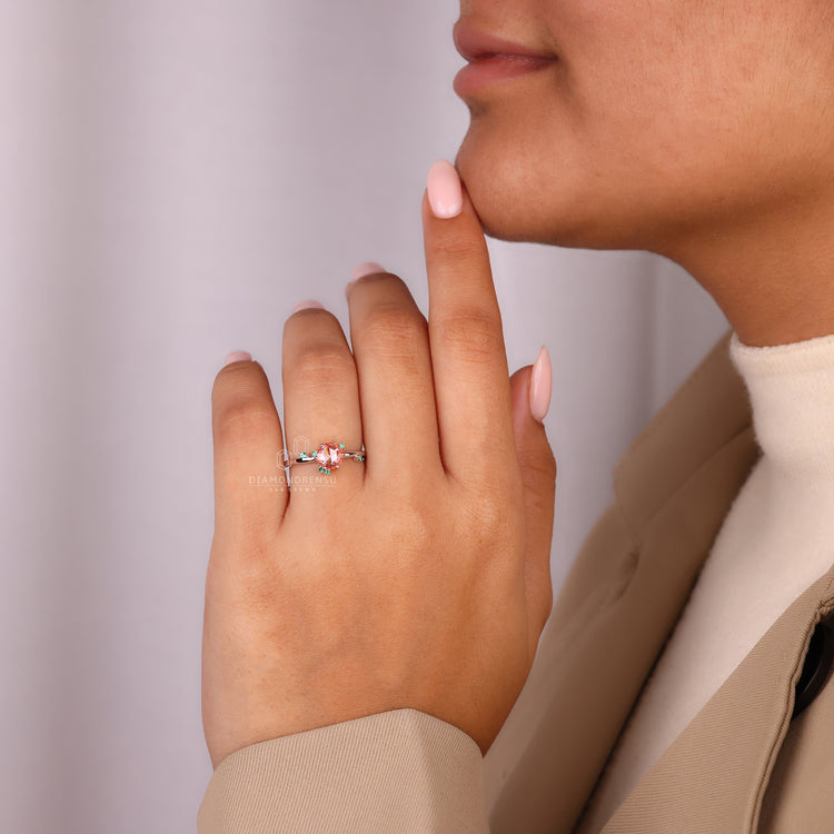 Lab grown diamond ring with emerald side stones and peach gemstone.