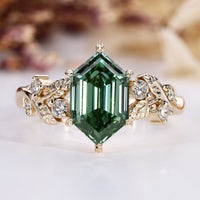 Hexagon diamond ring with green center stone and round side stones.