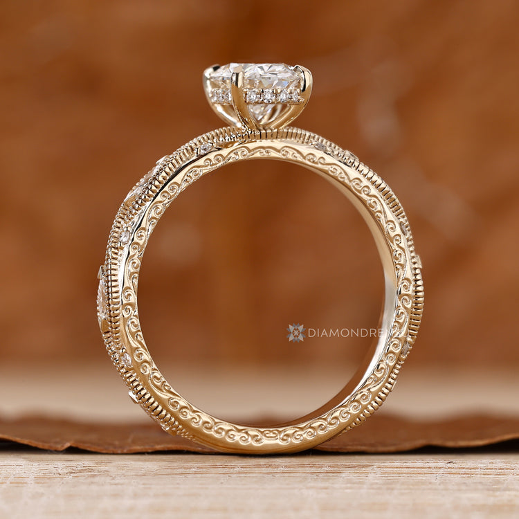 Oval diamond ring with marquise side stones and milgrain.