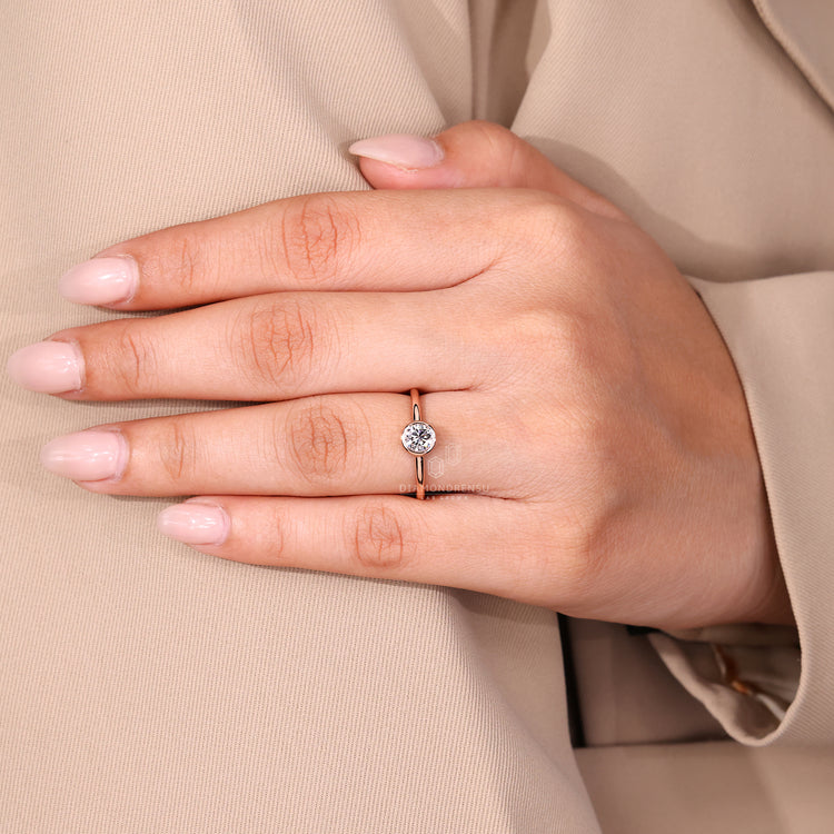 Round cut diamond ring with bezel set solitaire band.