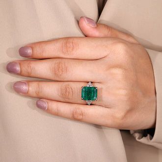 Emerald ring with round diamond side stones.
